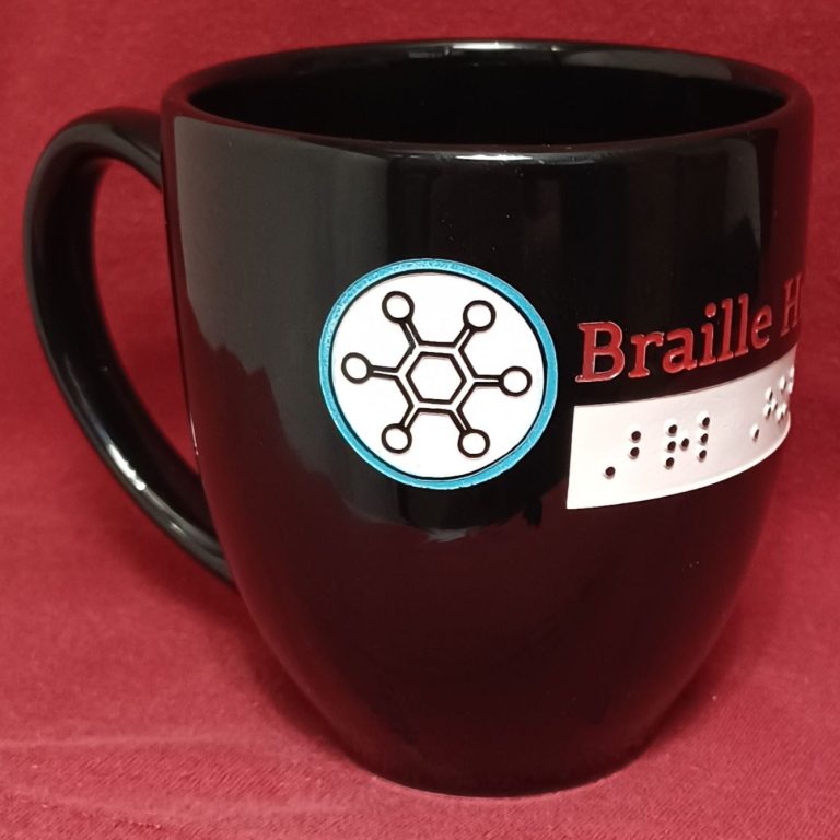 Black coffee mug with color print and braille etched in the mug. Reads Braille Hub USA.
