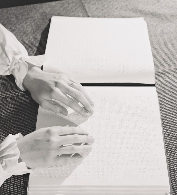 Hands resting on an open braille book reading a specific page.